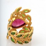 A gold ring with green leaves and a pink stone.