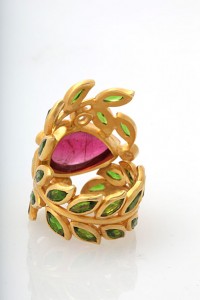 A gold ring with green leaves and a pink stone.