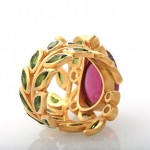 A gold ring with green and pink stones.