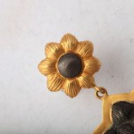 A close up of the top part of a gold earring