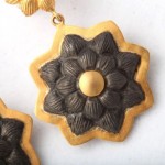 A pair of earrings with black and gold flowers.