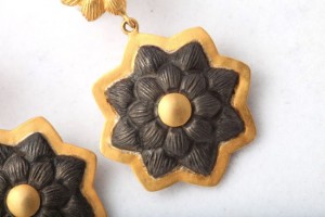 A pair of earrings with black and gold flowers.