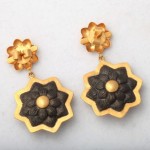 A pair of earrings with gold and black flowers.