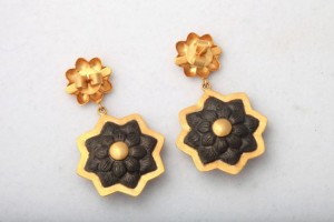 A pair of earrings with gold and black flowers.
