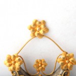 A yellow flower and metal ornament on the wall.