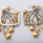 A pair of earrings with gold flowers hanging from the bottom.