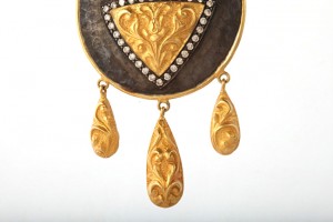 A gold and diamond pendant with three drops.