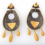 A pair of earrings with gold and black designs.