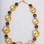 A gold necklace with black stones on it.