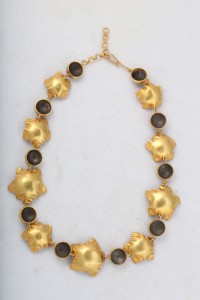 A gold necklace with black stones on it.