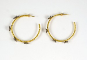 A pair of gold hoop earrings with bees on them.