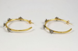 A pair of gold and diamond hoop earrings.