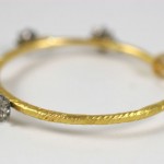 A gold and diamond bangle bracelet with four diamonds.