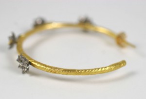 A gold and diamond bangle bracelet with four diamonds.