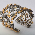 A metal bracelet with flowers and swirls.