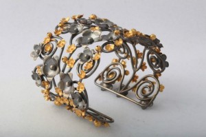 A metal bracelet with flowers and swirls.
