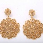 A pair of gold earrings with large, round diamonds.