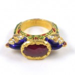A gold ring with red stone and blue enamel.