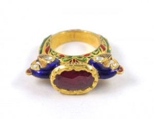 A gold ring with red stone and blue enamel.