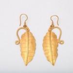 A pair of gold earrings with leaves hanging from them.