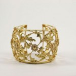 A gold bracelet with leaves and flowers on it.