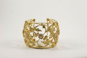 A gold bracelet with leaves and flowers on it.