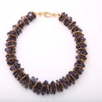 A necklace with purple beads and gold wire.