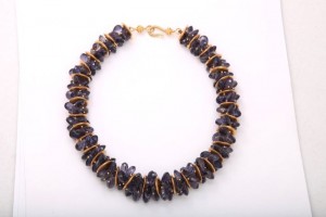 A necklace with purple beads and gold wire.