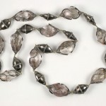 A long necklace of silver beads on a white background