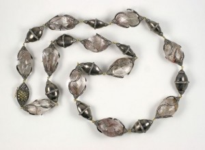 A long necklace of silver beads on a white background