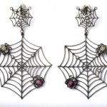 A pair of spider web earrings with pink stones.