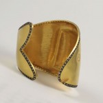 A gold cuff with black diamonds on it.