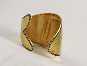 A gold cuff with black diamonds on it.