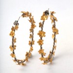 A pair of gold flower hoops with silver posts.