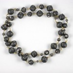 A long necklace of black beads on a white background