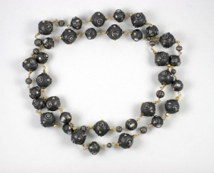 A long necklace of black beads on a white background