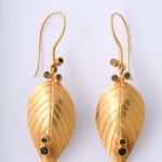 A pair of gold earrings with green stones.