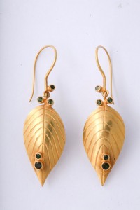 A pair of gold earrings with green stones.