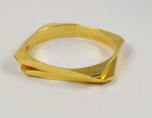 A gold ring with two intersecting sections on top of it.