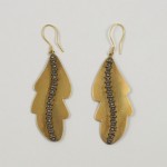 A pair of earrings with gold leaf and black beads.