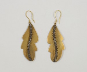 A pair of earrings with gold leaf and black beads.