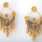 A pair of gold earrings with flowers and leaves.