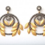 A pair of earrings with gold and diamond leaves.