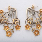 A pair of earrings with gold flowers and leaves.