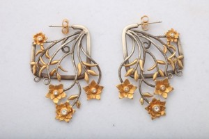 A pair of earrings with gold flowers and leaves.