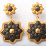 A pair of earrings with gold and black flowers.