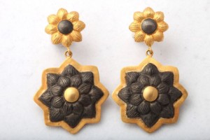 A pair of earrings with gold and black flowers.