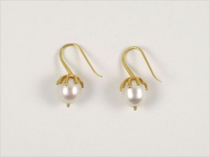A pair of gold earrings with pearls on them.