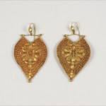 A pair of gold earrings with a heart shaped design.