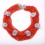 A necklace with orange beads and white flowers.